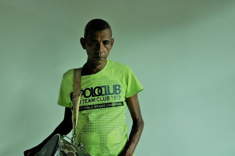 Retrato de um homem de camiseta verde-limão diante de uma parede verde.