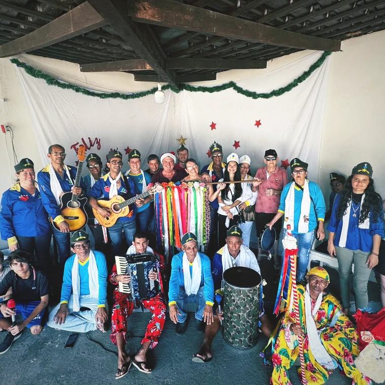 Foto de grupo da Companhia de Santos Reis, com bandeira, violões e sanfona.