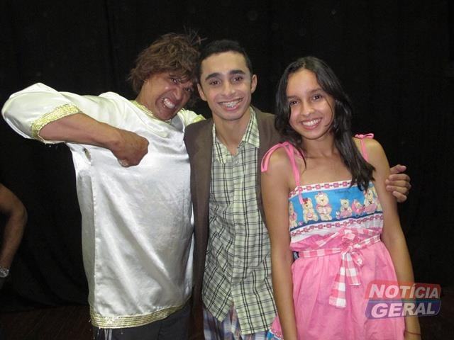 Três atores do grupo, de figurino, posam juntos depois de uma apresentação.