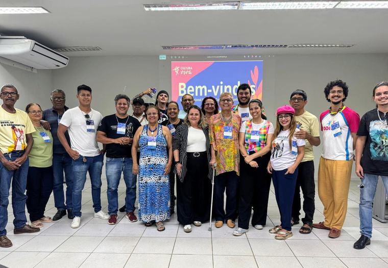 Encontro da rede Cultura Viva: participantes posam diante de um telão com a palavra “Bem-vindos”.