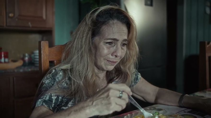 Cena do curta Camadas: uma mulher come sozinha à mesa de uma cozinha.