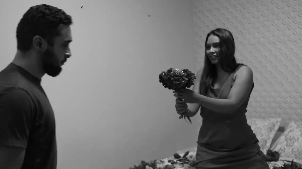 Cena em preto e branco do curta Flores: uma mulher estende um buquê de flores a um homem.