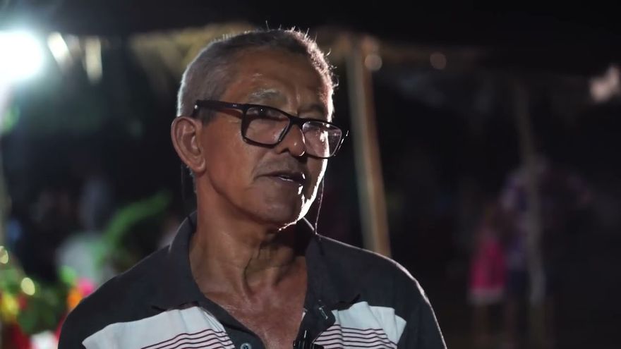 Cena do documentário Devoção e Folia de Reis: um senhor de óculos fala à câmera durante uma festa à noite.